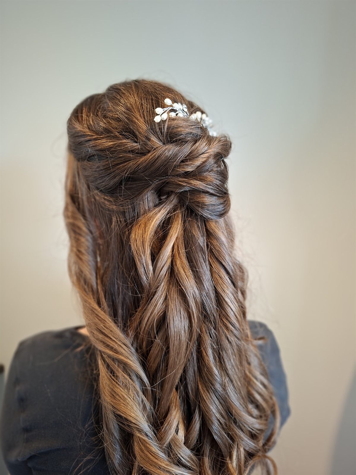 Lang bruin haar, halfopgestoken met gedraaide lokken, krullen en kleine parelspeldjes