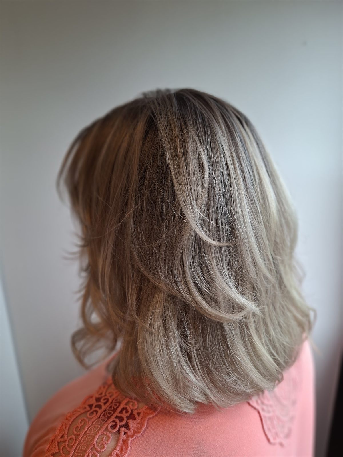 Halflang, gelaagd blond haar met een zachte slag