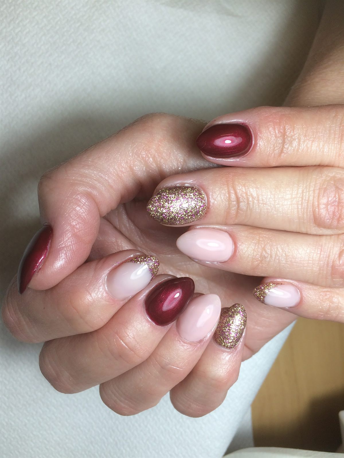 Nagels in bordeauxrood en lichtroze, met gouden glitternagels