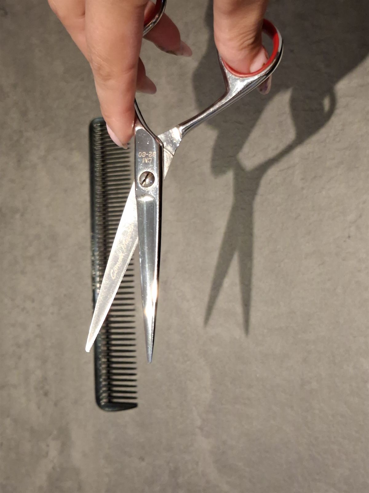 Een hand houdt een kappersschaar boven een kam